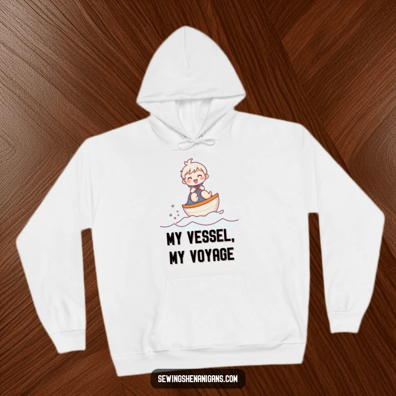 Funny hoodie depicting a joyful character sailing a thimble boat across fabric, offering warmth and humorous charm.