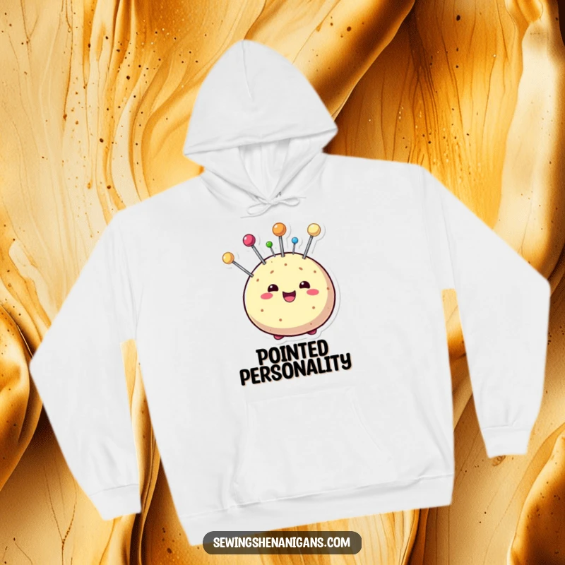 Funny hoodie showcasing a beaming pin cushion character with colorful pins sticking out playfully, offering warmth and creative charm.