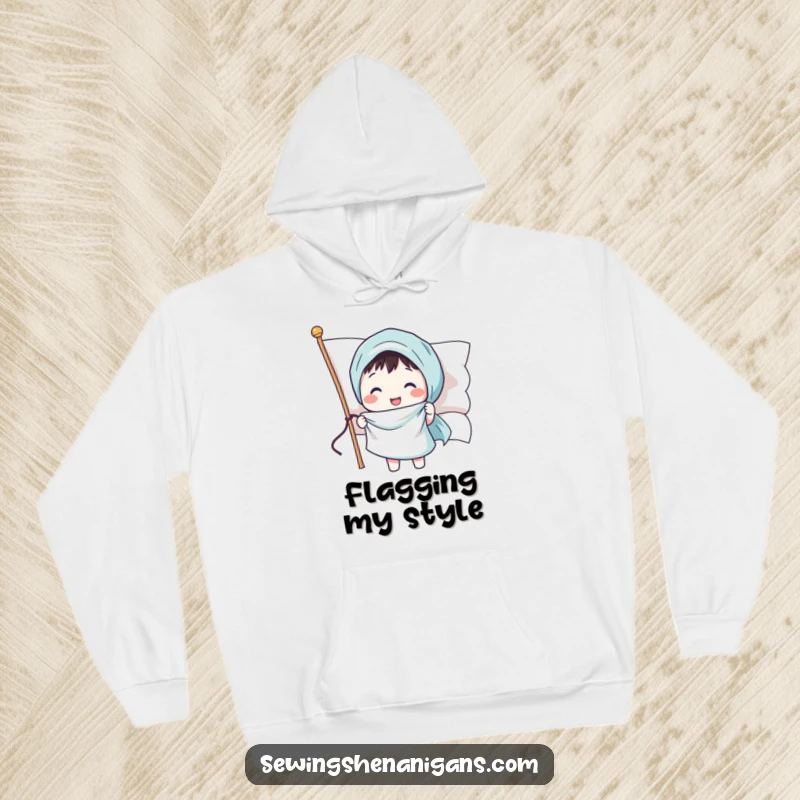 Funny hoodie depicting a joyful character sewing a smiling face onto a waving flag, offering warmth and patriotic humor.