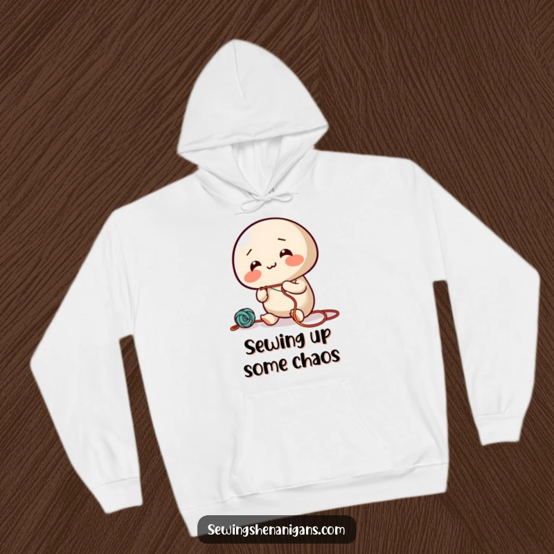 Funny hoodie with a giggling needle character energetically threading colorful string, perfect for a cozy and amusing wear.