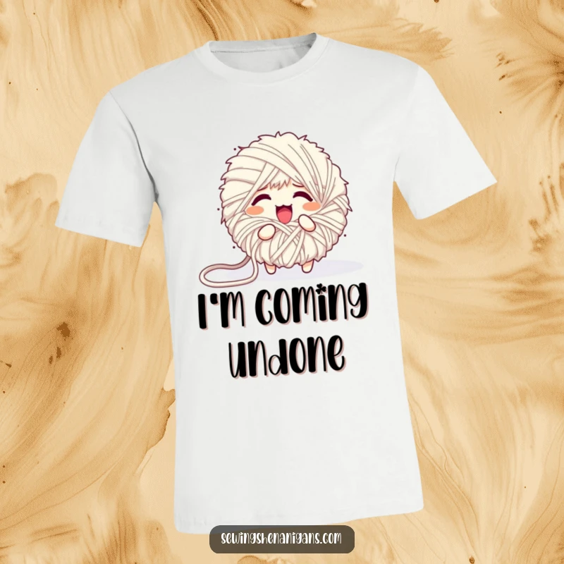 Funny t-shirt depicting a fluffy yarn ball character comically unraveling into a tangled mess, embodying creative disarray.
